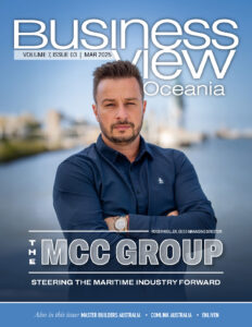 Picture of a magazine front cover. There is a man with folded arms looking at the camera with a city blurred in the background. The title is Business View Oceania. 