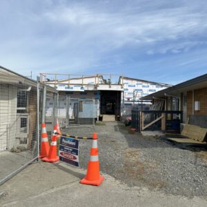 A construction site showing a building in progress. Traffic cones and a construction site sign in the foreground.